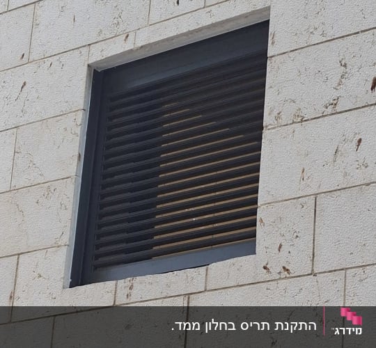 מסתור אלומיניום כהה עם שלבי רפפות בקיר חיצוני מחופה אבן